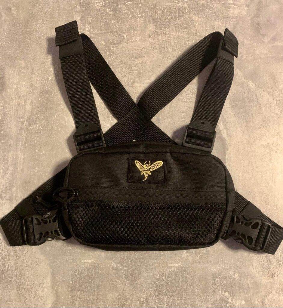 Czarna saszetka typu chest rig ze złotym logo firmy. Projektowanie sprzętu nośnego, akcesoriów oraz szycie prototypów na zamówienie.